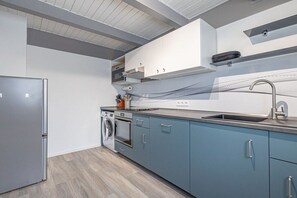 A modern kitchen with a built-in oven, a washing machine, and a stainless steel sink. - Holiday home with 2 bedrooms (Nordstrand)