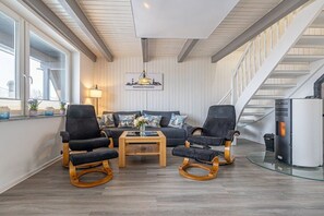 A modern living room with a sofa set, two rocking chairs, a coffee table, and a fireplace. - Holiday home with 2 bedrooms (Nordstrand)