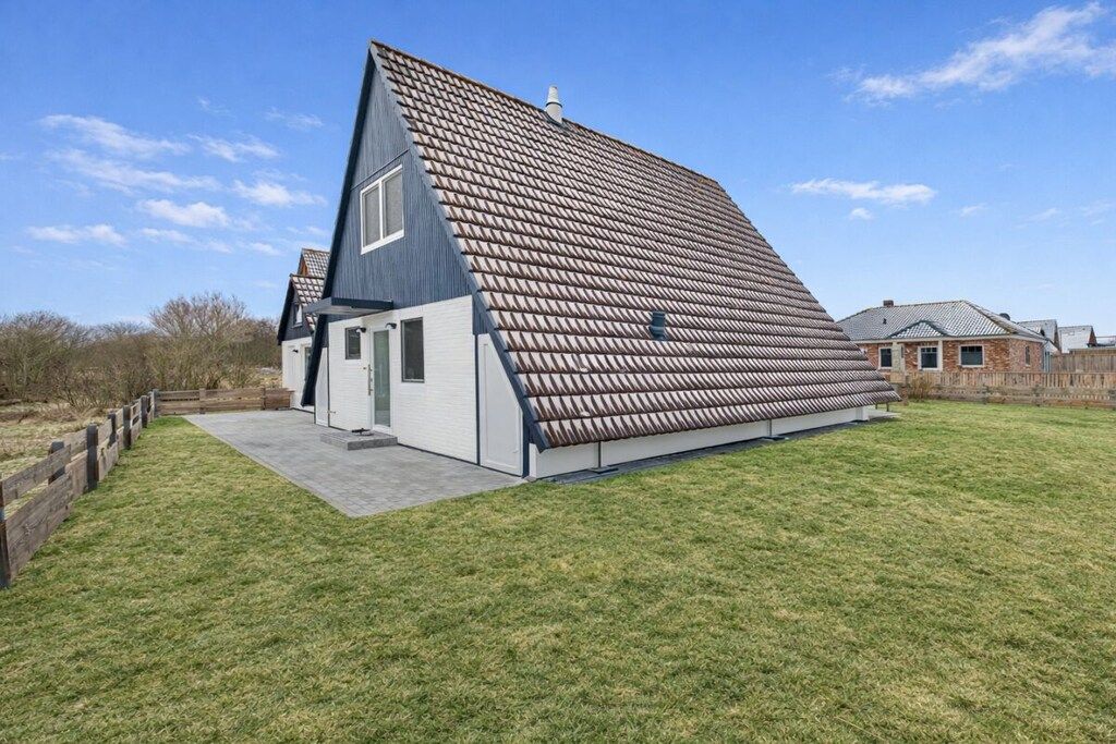 Een modern huis met een schuin dak, een klein portaaltje en een verzorgd gazon.