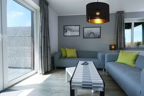 Ein modernes Wohnzimmer mit einer Couch, einem Couchtisch und einer Pendelleuchte.