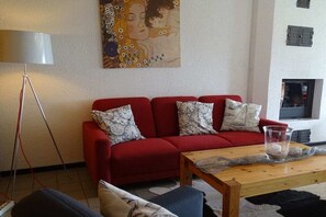 A living room with a red sofa, patterned cushions, a wooden coffee table, a floor lamp, and a painting on the wall. - Holiday home in Schlei with 3 bedrooms (Kappeln Stadt)