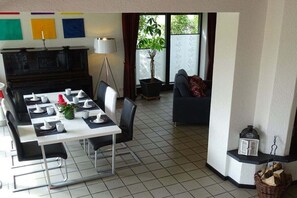 A dining area with a table set for four, a black piano, a lamp, and a sofa in the background. - Holiday home in Schlei with 3 bedrooms (Kappeln Stadt)