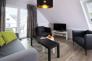A modern living room with a sofa, two armchairs, a coffee table, and a television. - Holiday apartment with 2 bedrooms (Carolinensiel)