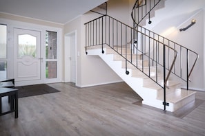 Een modern interieur met een spiltrap, houten vloeren en een eethoek.
