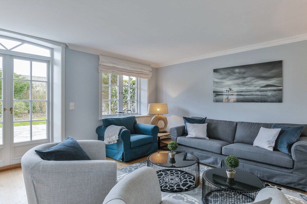 A living room with a sofa, armchairs, a coffee table, and a painting on the wall.