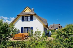 A traditional house with a thatched roof, a wooden bench, and a clear blue sky. - Thatched House Calappa (Zierow)