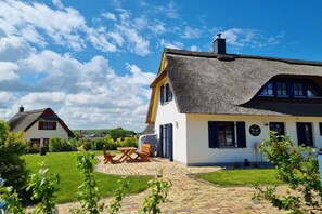 A house with a thatched roof, a paved patio, and a well-maintained lawn. - Thatched House Calappa (Zierow)