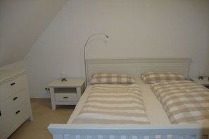 A bedroom with a single bed, a nightstand, a dresser, and a lamp. - Thatched House Calappa (Zierow)