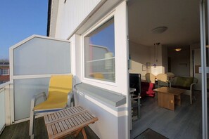 A room with a window, a chair, a table, and a sofa. - Seestern No. 4 Apartment House Seestern (Norderney)