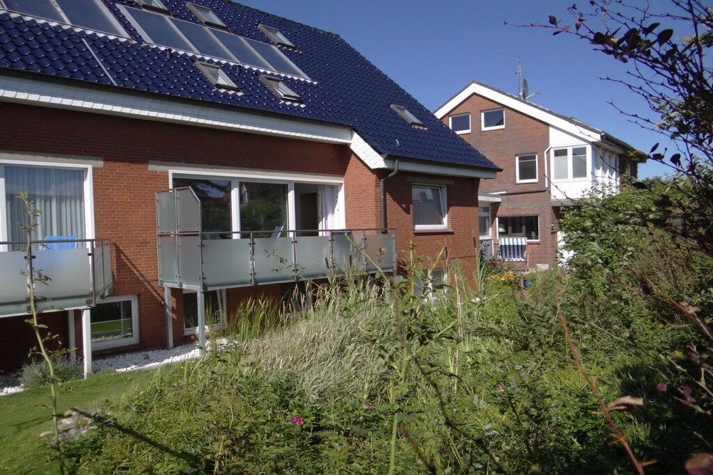 Un edificio residencial con techo inclinado, paneles solares y un balcón.