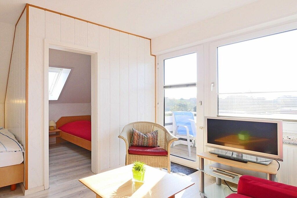 Une petite chambre comprenant un lit, une télévision, une chaise et une table.
