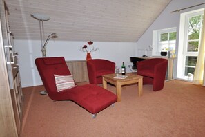 Una habitación con dos sillones rojos, una mesa de centro de madera y un jarrón con flores.