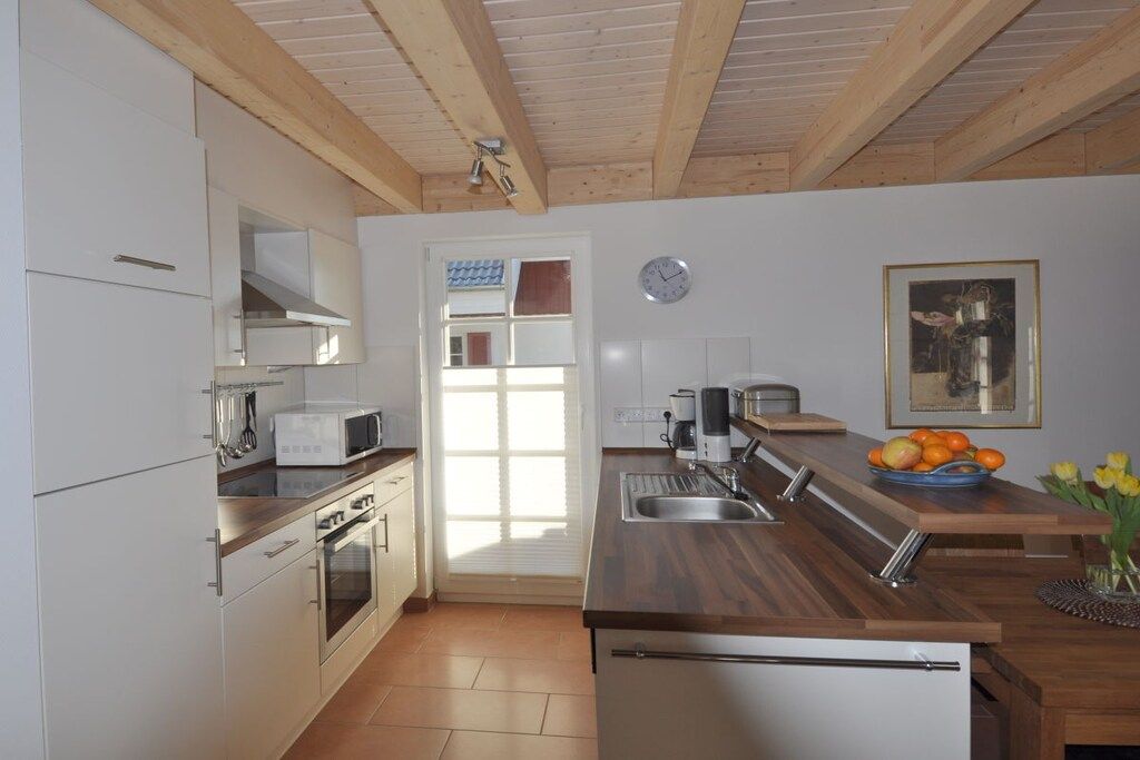 A modern kitchen with white cabinetry, stainless steel appliances, and a wooden countertop.
