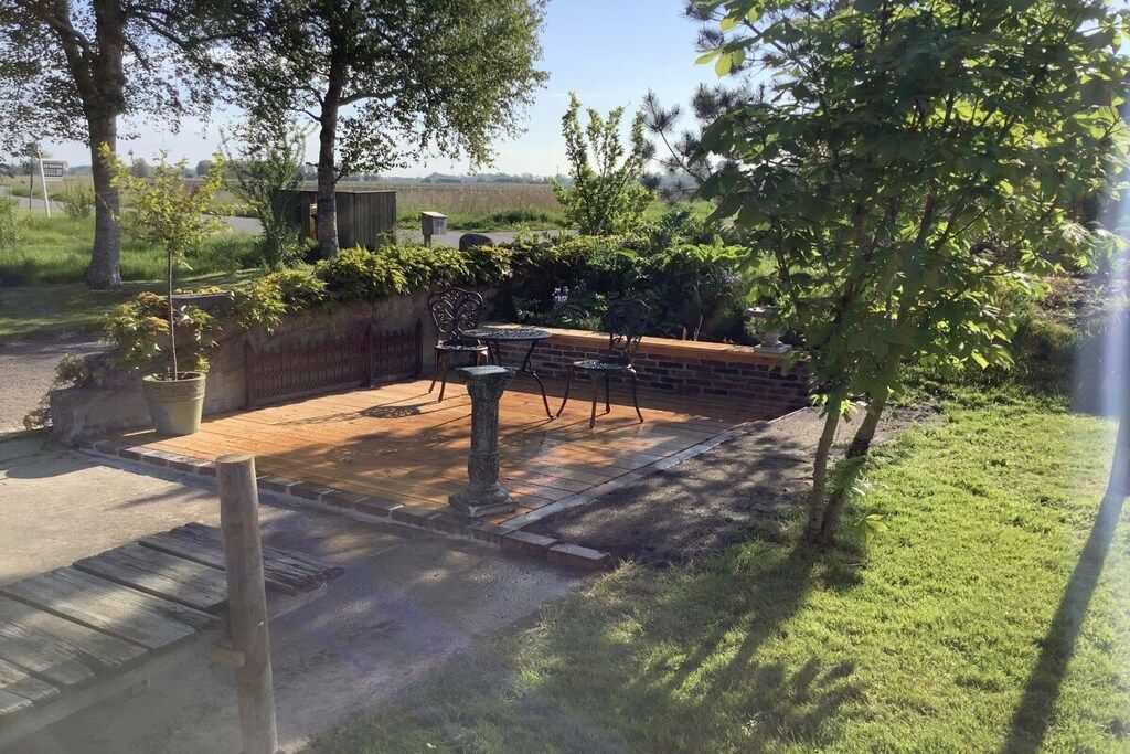 Eine Terrasse mit Backsteinmauer, Metallstühlen und einem Tisch.