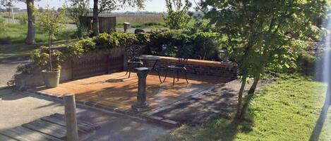A patio area with a brick wall, metal chairs, and a table.