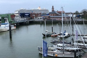 A marina with various boats docked, a large cruise ship in the background, and a building with a red roof. - House of Lord Nelson (Cuxhaven-Döse)