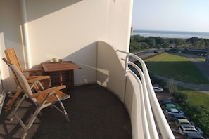 A balcony with a table and chairs, a view of a parking lot, and a grassy area. - House of Lord Nelson (Cuxhaven-Döse)