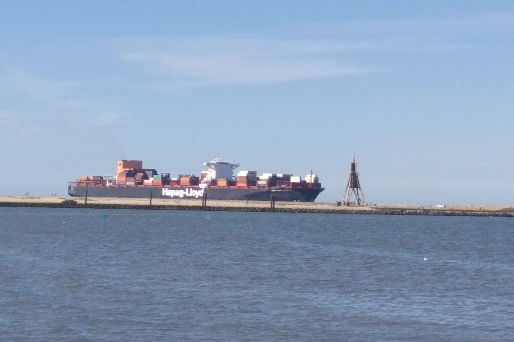 A cargo ship docked at a port with a clear sky.