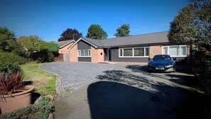 A residential house with a driveway, a parked car, and a garden. - Bungalow Annex - Sleeps 6 With Countryside Views (Tarporley)