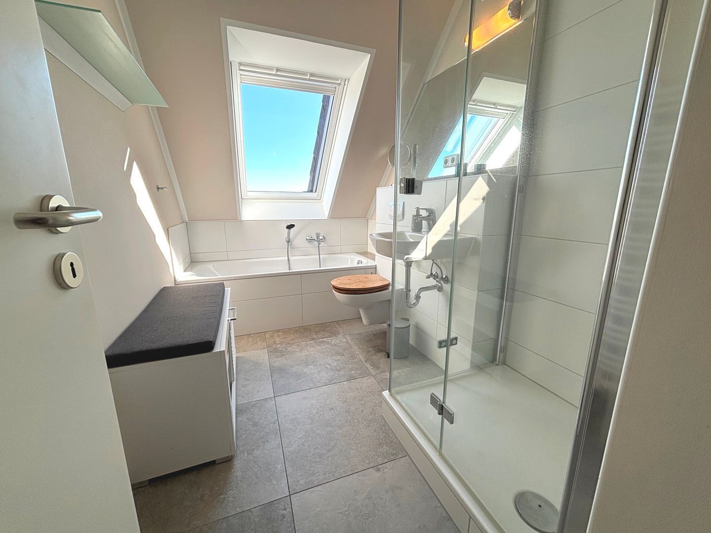 Ein modernes Badezimmer mit Glasdusche, einer Badewanne und einem Fenster für natürliches Licht.