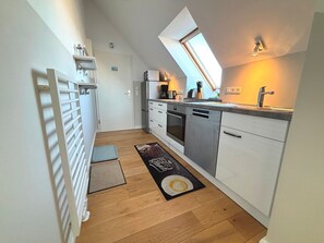 Cocina compacta con tragaluz, lavavajillas y una encimera con lavabo.