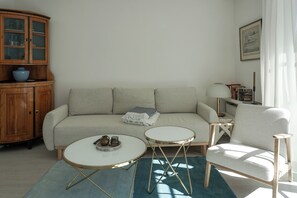A living room with a sofa, two side tables, a cabinet, and a lamp. - Cozy Vacation Rental at Friesenring 17c in Wenningstedt (Wenningstedt-Braderup (Sylt))