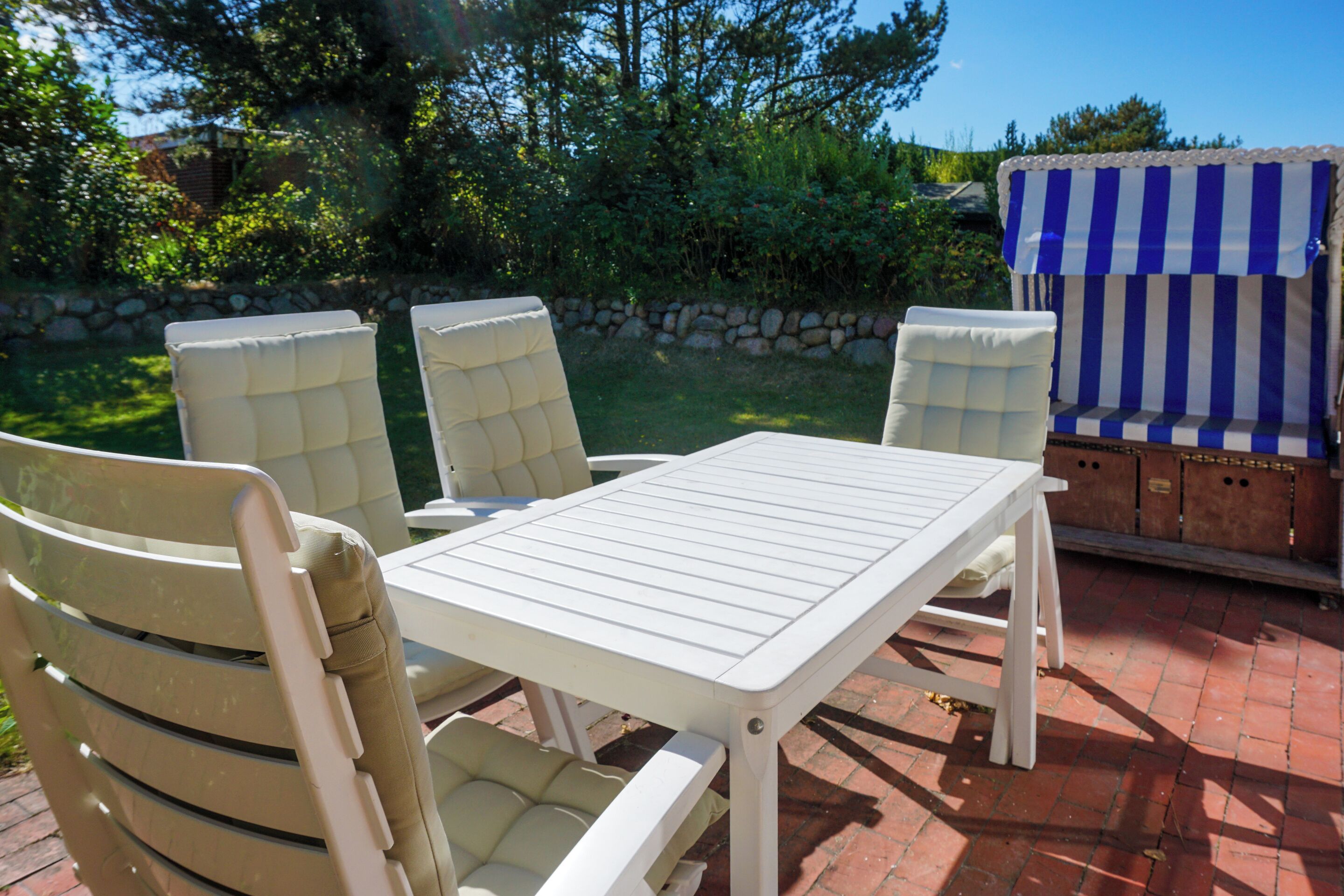 An outdoor patio with a white table and four beige chairs.