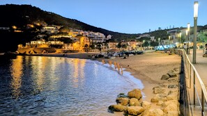 Eine Küstenstadt im Abendlicht mit Gebäuden, einem Strand und einer felsigen Küste.