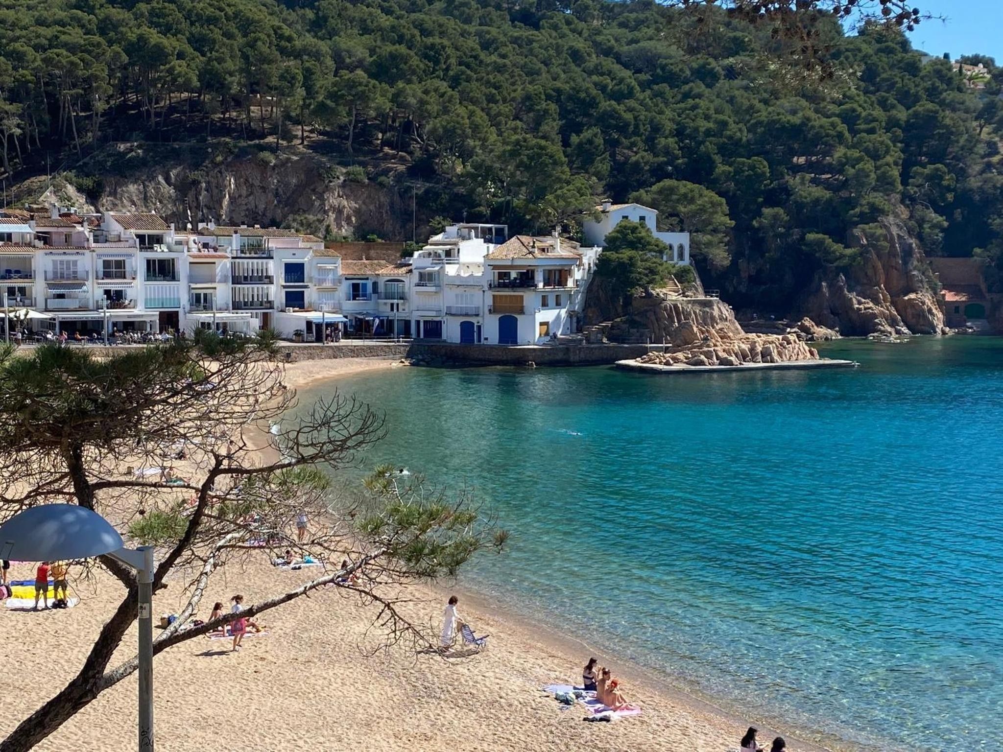 Una zona costera con edificios, una playa y agua azul cristalina.