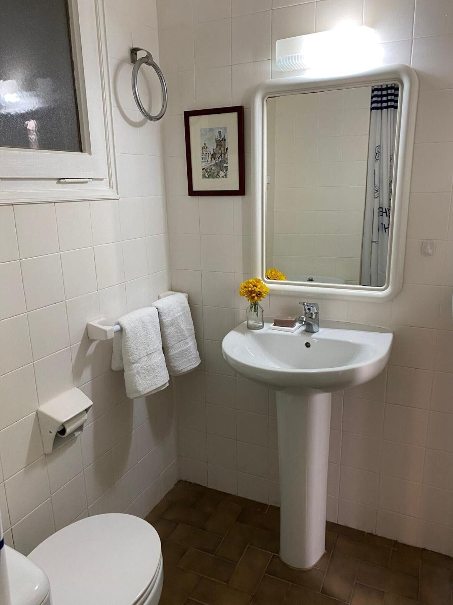 Ein Badezimmer mit einem weißen Waschbecken, einem Spiegel, einer Toilette und einem Handtuchhalter.