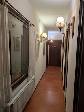 A narrow hallway with a radiator, a door at the end, and wall-mounted lamps. - Apartment 'La Mejor Terraza De Tamariu' with Sea View, Wi-Fi and Air Conditioning (Tamariu)