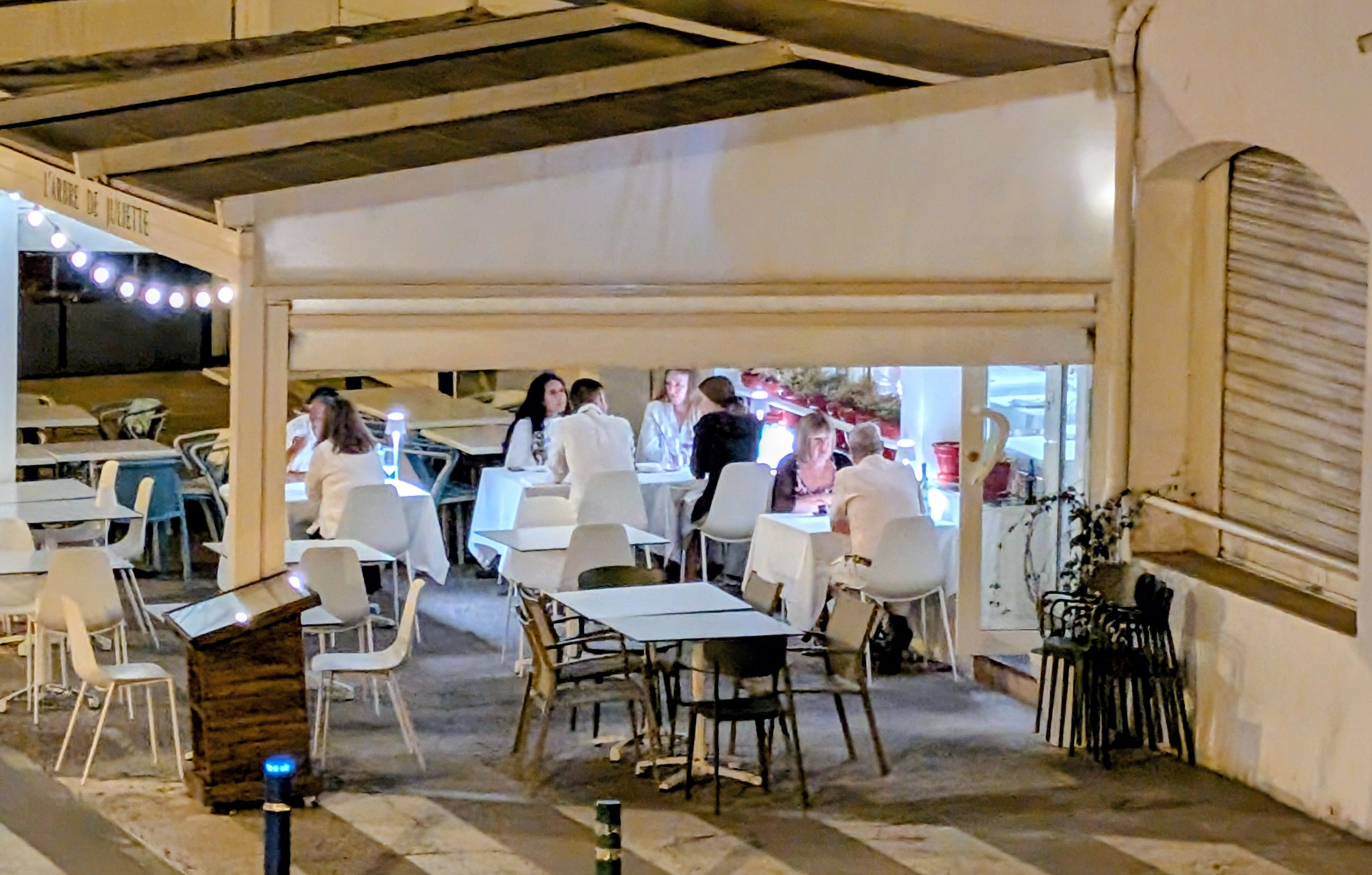 Un'area pranzo all'aperto con tavoli e sedie, una zona riparata e vista sulla strada.