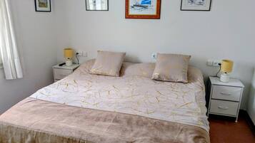 Een slaapkamer met een bed, twee nachtkastjes en een bedbank.