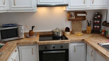 Una cocina con armarios blancos, un microondas, una estufa y un fregadero.