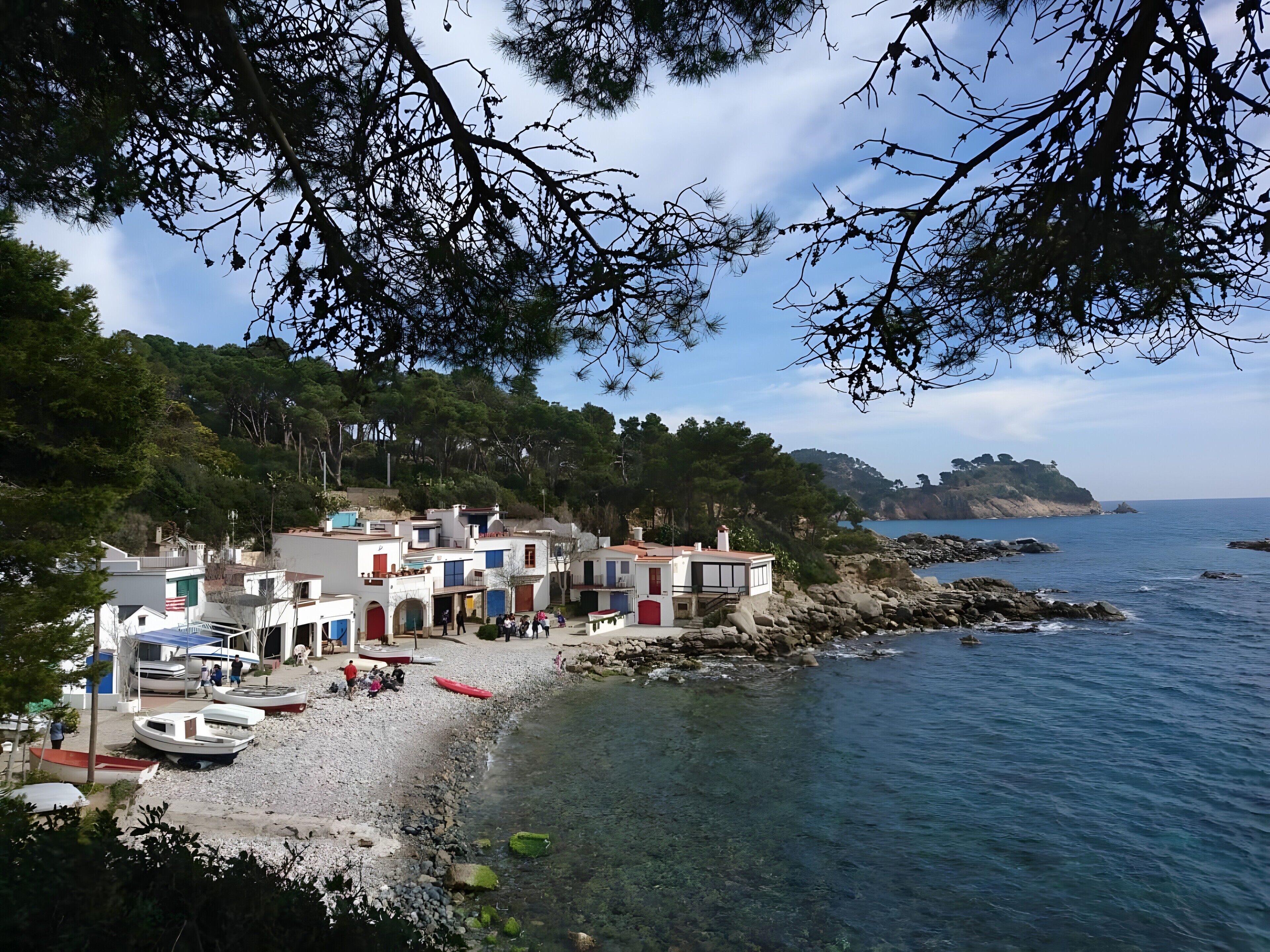 Un village côtier avec des bâtiments qui bordent la plage, une eau claire et un paysage rocheux.