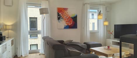 Una sala de estar moderna con un sofá, un televisor, una mesa de comedor y una chimenea.