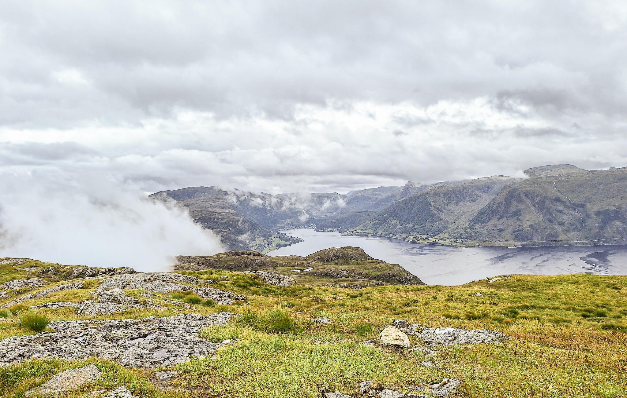 Paesaggio montuoso con un lago e un cielo nuvoloso.