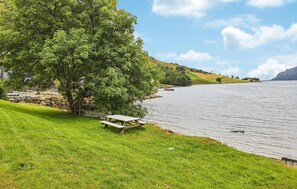 A lakeside picnic area with a bench, a stone wall, and a view of the water. - Stunning home in Stongfjorden with house a panoramic view (Stongfjorden)