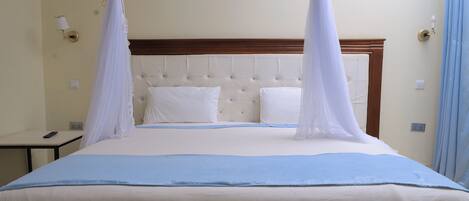 Una habitación de hotel con una cama con dosel, una mesita de noche y una lámpara.