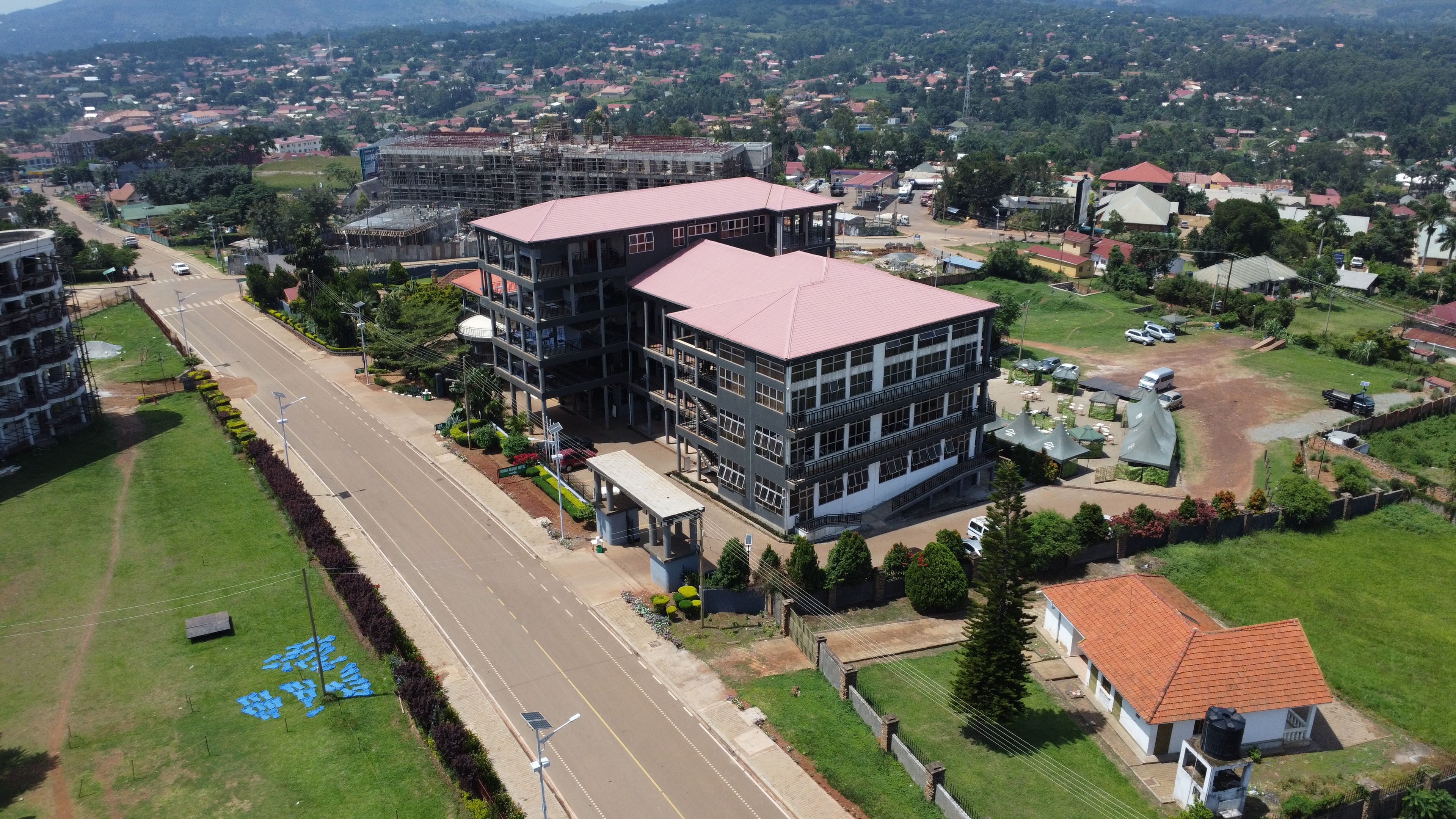 A multi-story building with a red roof, surrounded by a well-maintained lawn and a road.