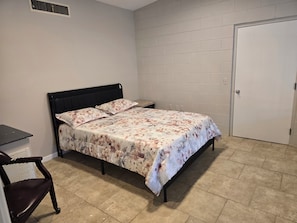 A bedroom with a bed, a chair, a door, and a wall with a vent. - Tremendous 2-bedroom house with AC in friendly Midland (Midland)