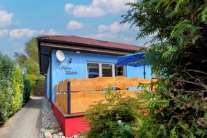 Ein blaues Gebäude mit rotem Dach, Holzzaun und einer Satellitenschüssel.