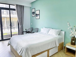 Una camera da letto con un letto, un comodino, una sedia e vista su un balcone.