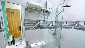 Une salle de bain moderne avec une douche à parois de verre, des toilettes blanches, un lavabo et un porte-serviettes.