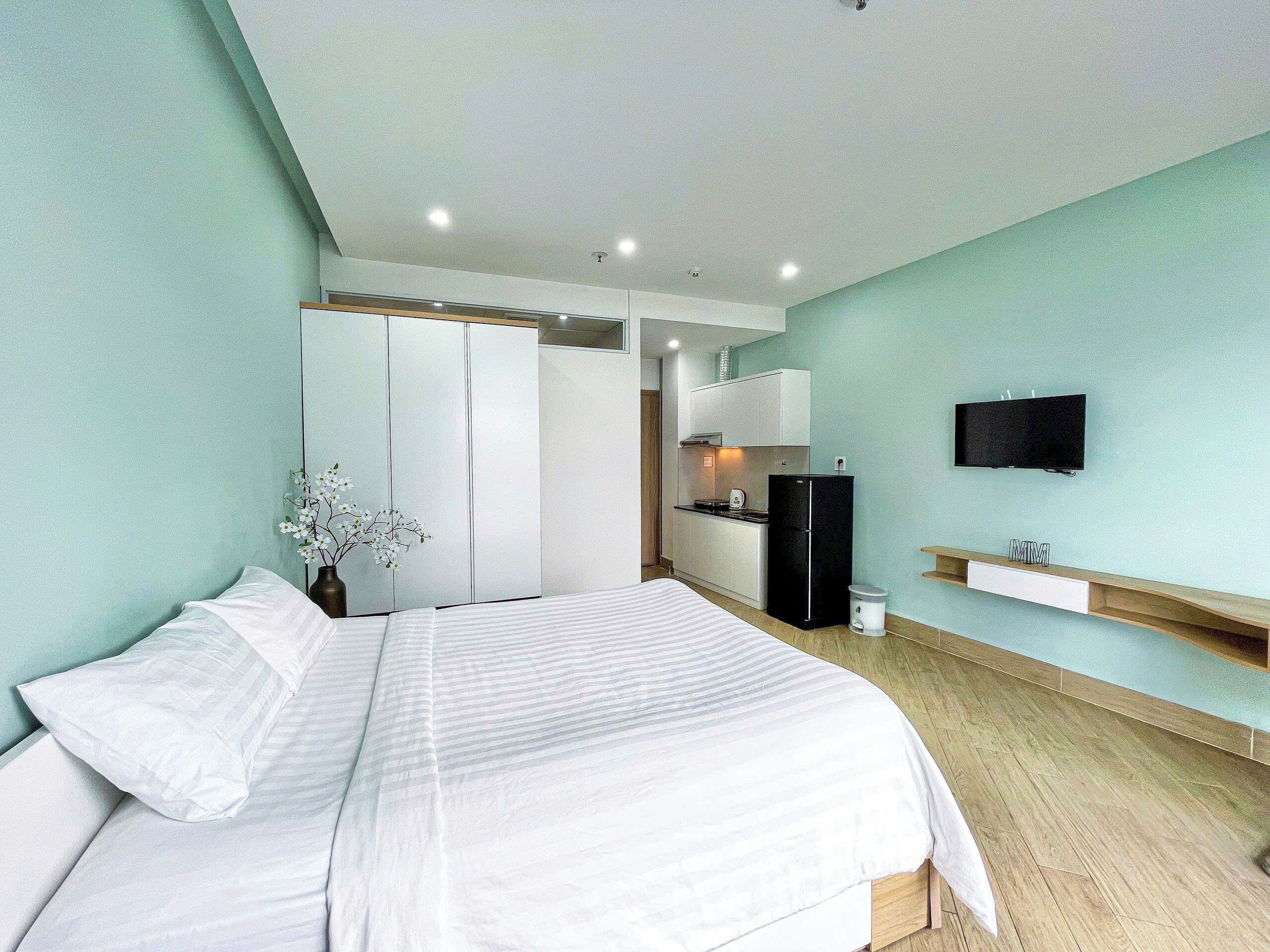 A bedroom with a bed, a TV, a small kitchenette, and a wardrobe.