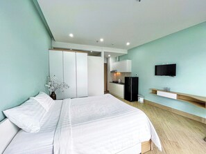 Quarto com cama, televisão, pequeno kitchenette e guarda-roupa.