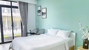 Une chambre à coucher avec un lit, une petite table, deux chaises, une table de chevet et un vase avec des fleurs.