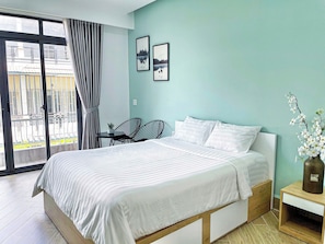 Una camera da letto con un letto, un tavolino, due sedie, un comodino e un vaso con fiori.