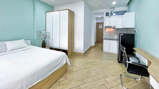 Une chambre d’hôtel comprenant un lit, un bureau, une kitchenette et une armoire.