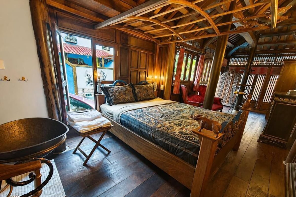 Ein Zimmer mit Holzrahmen, einem Bett, einem Esstisch und Blick ins Freie.